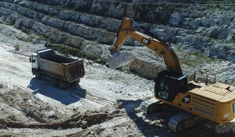 Excavator working the white quartz quarry face